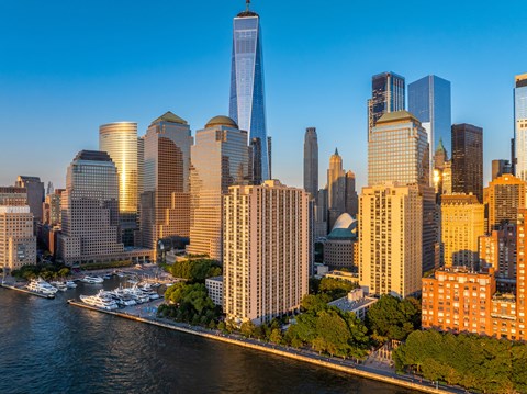 A city skyline with a river in the foreground and boats docked.