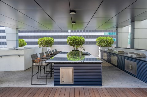 A modern outdoor kitchen with a bar and chairs.