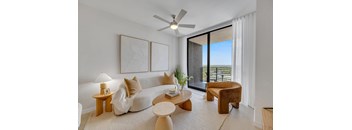 A living room with a white couch, a wooden coffee table, and a ceiling fan.