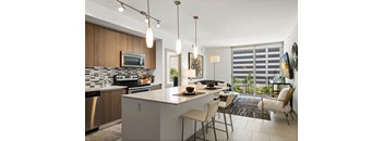A modern kitchen with a large island and a dining area with chairs.