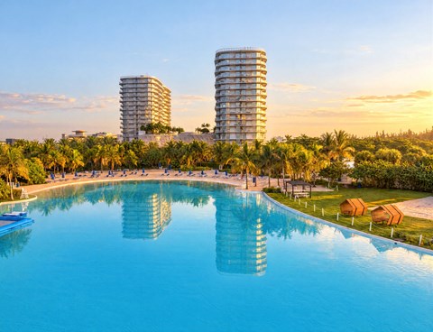 A large swimming pool in the foreground with two buildings in the background.