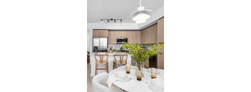 A modern kitchen with a dining table set for two.
