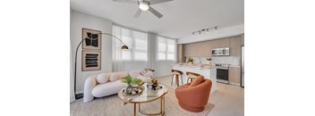 A modern living room with a white sofa, a coffee table, and a kitchen in the background.