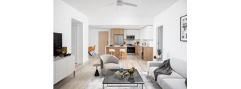 A modern living room with a grey sofa, a glass coffee table, and a television.