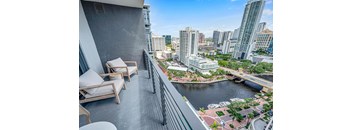 A balcony with chairs overlooks a river and cityscape.
