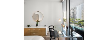 A modern room with a round mirror, a chair, and a table with a plant on it.