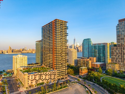 A cityscape with a prominent building in the foreground and a body of water in the background.