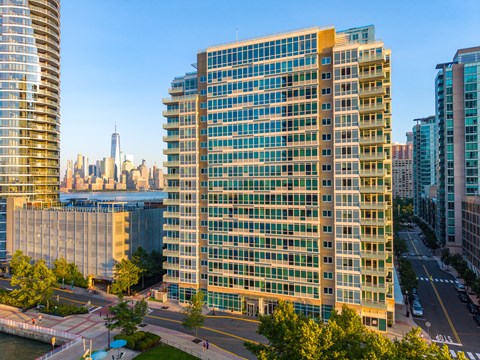 A tall building with many windows is in the foreground of a cityscape.