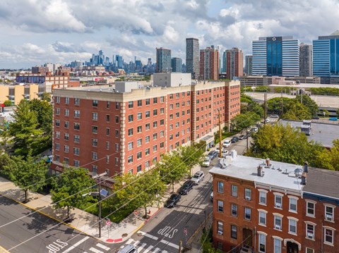 A red brick building is in the foreground of a city street.