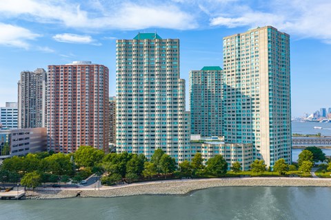 A cityscape with buildings and a body of water in the foreground.