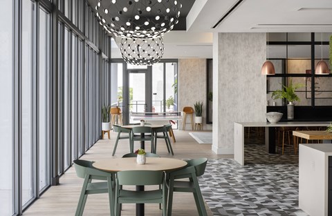A modern dining area with green chairs and a patterned floor.