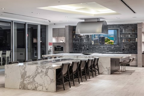 A modern kitchen with a marble island and chairs.