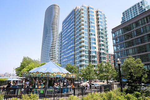 a carousel in a city park with tall buildings