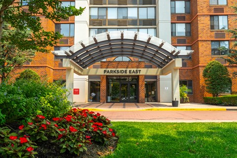 The front of a building called Parkside East with a red flower bed in front.