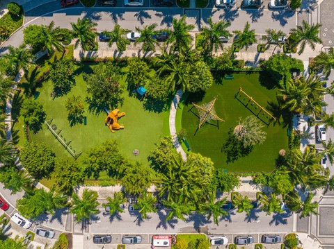 An aerial view of a park with a playground and palm trees.