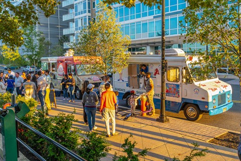 people walking on a street with food trucks