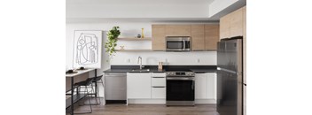 A modern kitchen with a black countertop and stainless steel appliances.