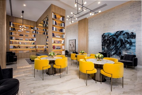 A modern dining room with a large table surrounded by yellow chairs.