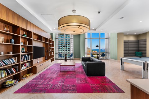 A living room with a pink rug and a television.