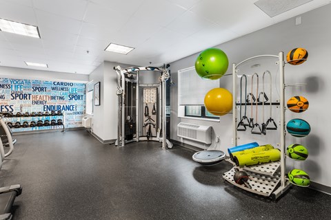 A gym with a variety of equipment and a wall covered in fitness related words.