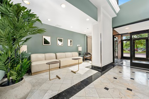 A white sofa with a black and white tiled floor and a green plant.