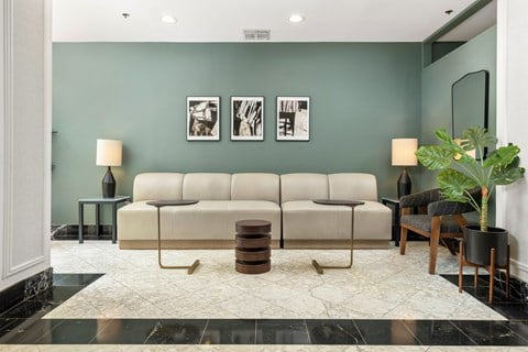 A living room with a beige sofa, two lamps, a table, and a potted plant.