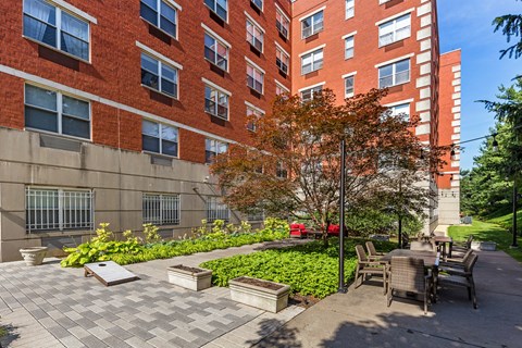 A red brick building with a tree and benches in front.