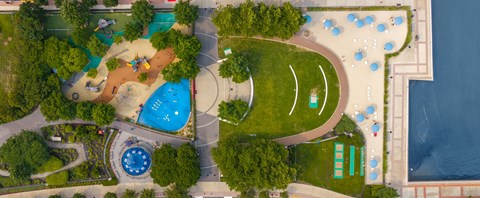 A park with a playground, a fountain, and a body of water.