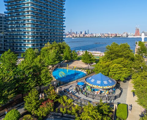 A view of a city from a high vantage point with a pool and a carousel.