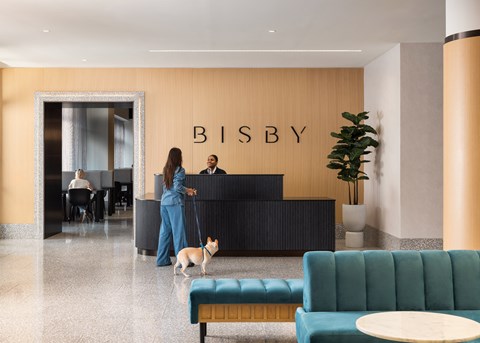 A woman is standing in front of a reception desk with a dog on a leash.