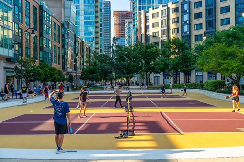 A man in a blue shirt is playing tennis on a court with a yellow line.