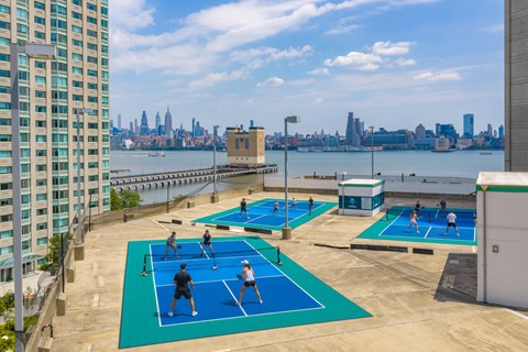 A group of people playing tennis on a court with a city skyline in the background.