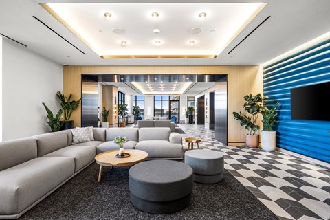 A modern living room with a grey sofa, a wooden coffee table, and a black and white checkered floor.
