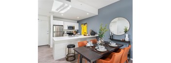 A modern kitchen with a dining table set for two.