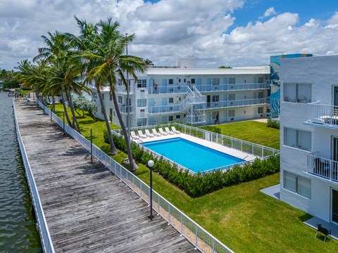 A pool is surrounded by a fence and a building is in the background.
