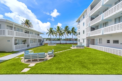 A white building with balconies and a green lawn in front.