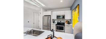 A modern kitchen with white cabinets and stainless steel appliances.