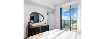 A bedroom with a large bed, a mirror, and a balcony with a chair.