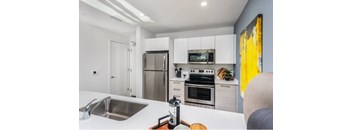 A modern kitchen with white cabinets and stainless steel appliances.