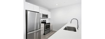 A modern kitchen with a stainless steel refrigerator, microwave, oven, and sink.
