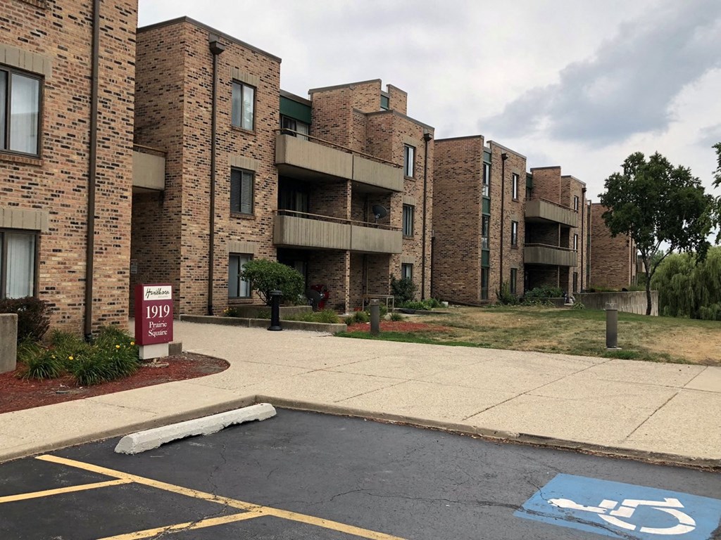 an apartment building with a parking lot and a handicapped sign