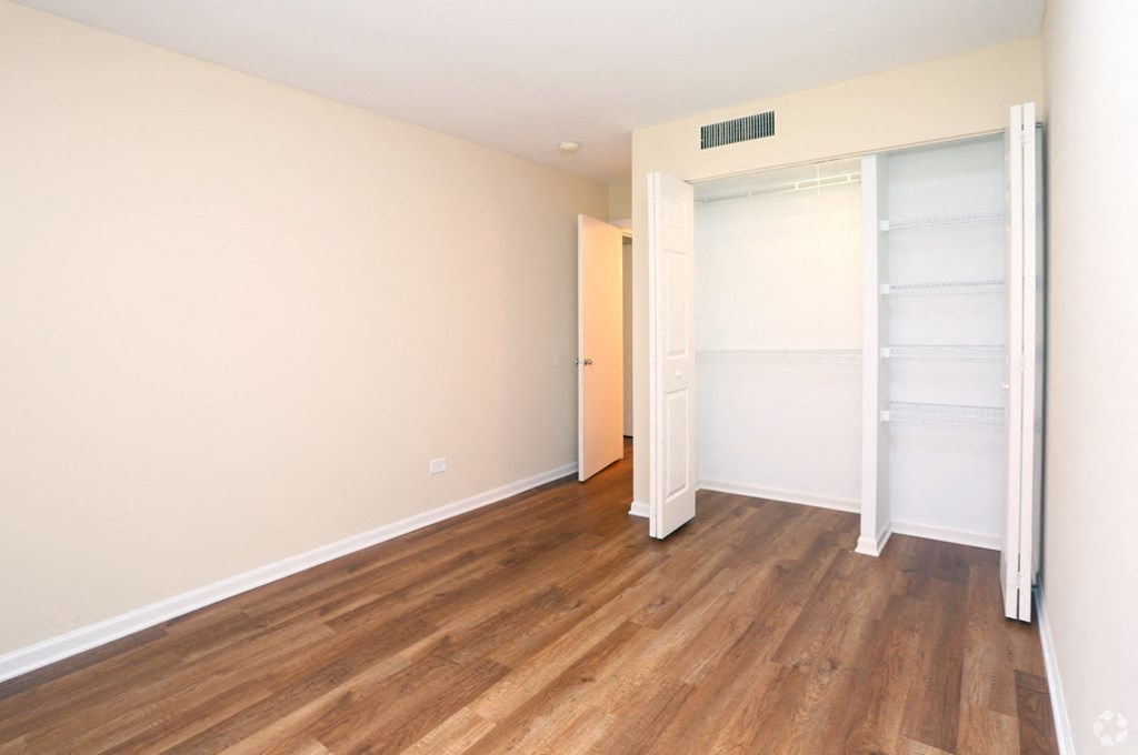 a bedroom with wood flooring and a closet with sliding doors