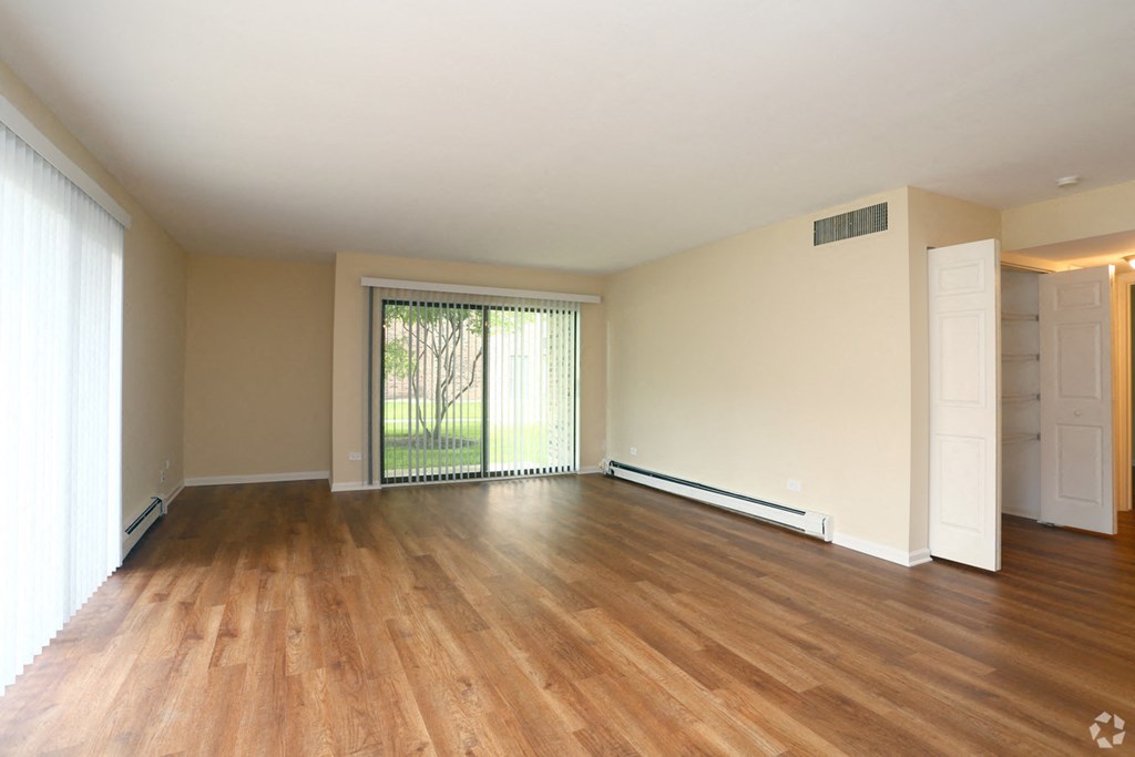 an empty living room with wood flooring and a large window