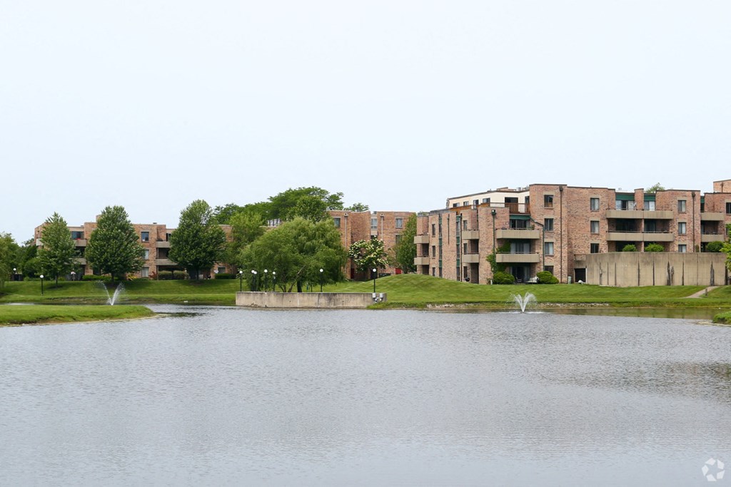 an apartment complex with a lake and fountain in front of it