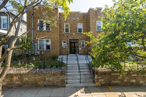 A brick building with a black iron fence and a stone wall in front.