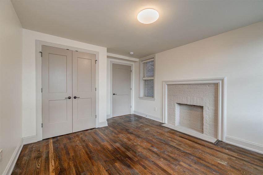 an empty living room with a white door and a fireplace