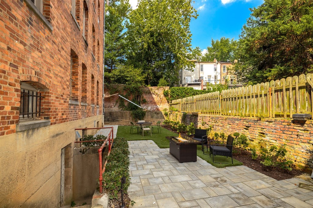 a backyard with a brick wall and a patio with a table and chairs