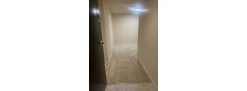 A hallway with a carpeted floor and a black door.