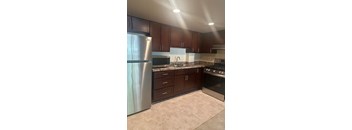 A kitchen with brown cabinets and a stainless steel refrigerator. at 2400 Pennsylvania Avenue Apartments, Washington