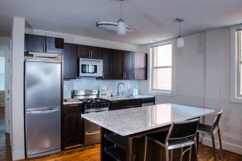 A kitchen with a refrigerator, microwave, oven, and sink.